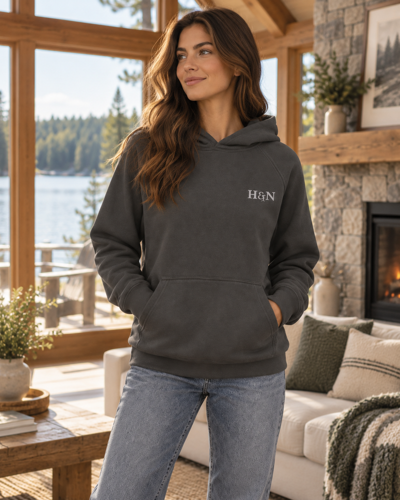 Heavyweight Hoodie in asphalt, worn by the lake window with the fire going.