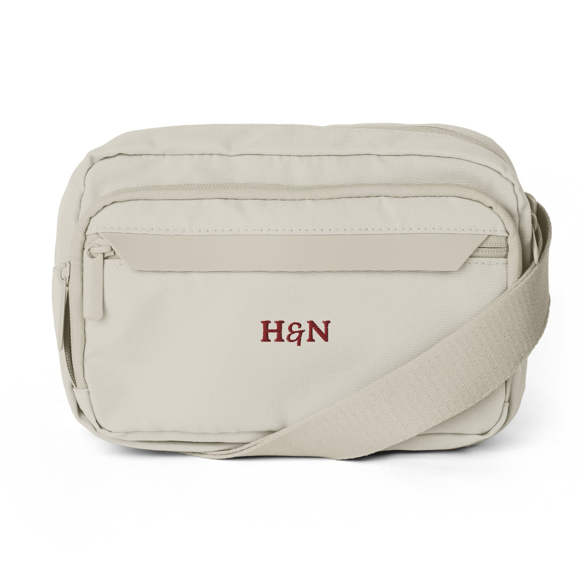 The Crossbody in natural stone, front view, embroidered monogram.