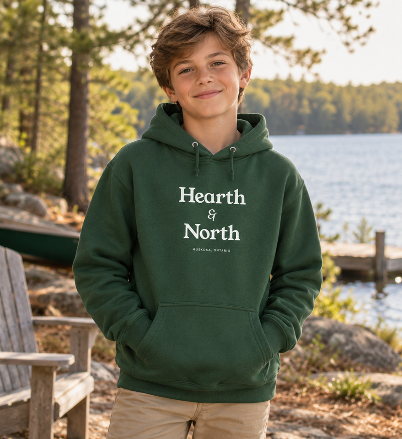 Wordmark Hoodie in spruce worn on a dock at the lake.
